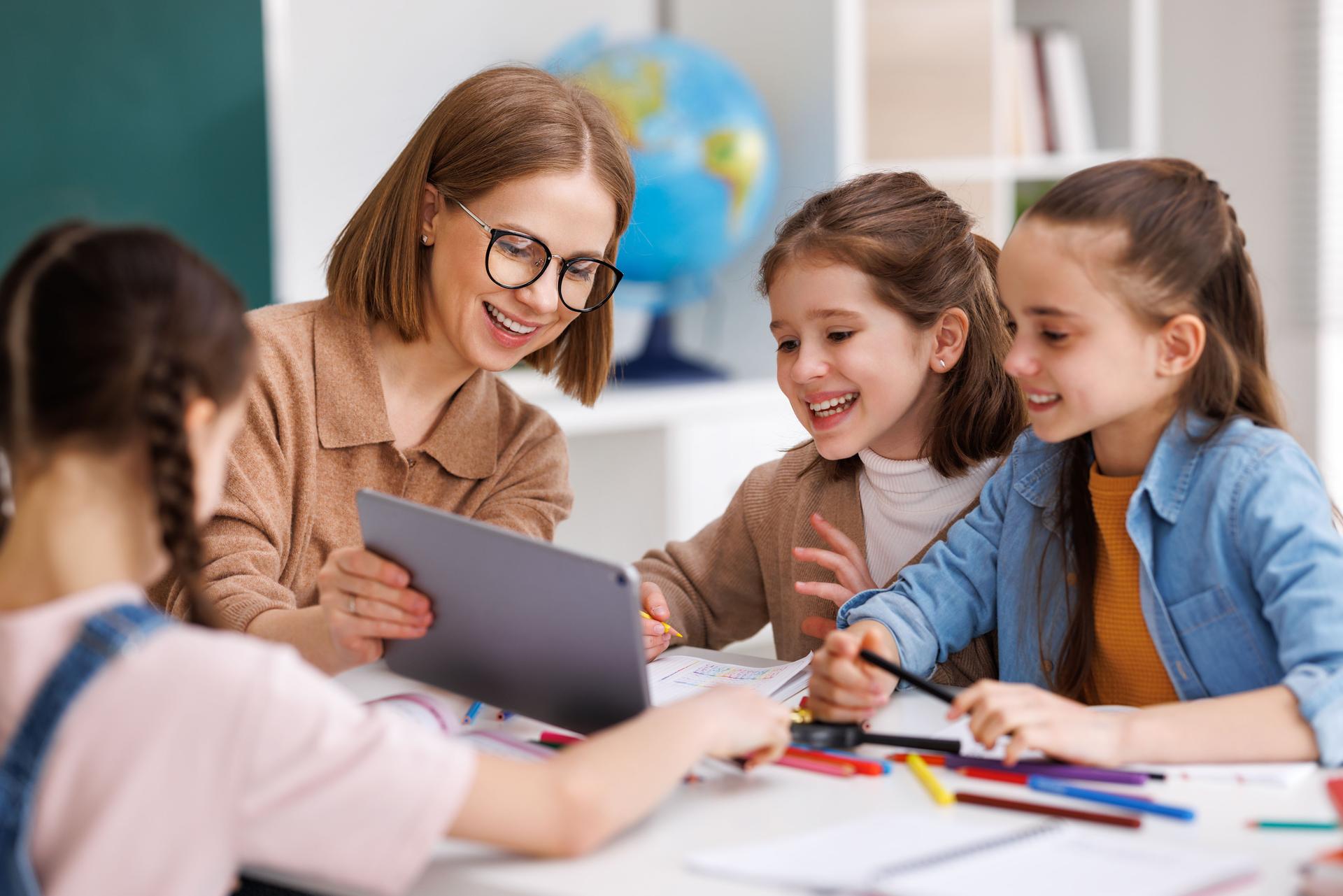Woman with tablet teaching children at school
